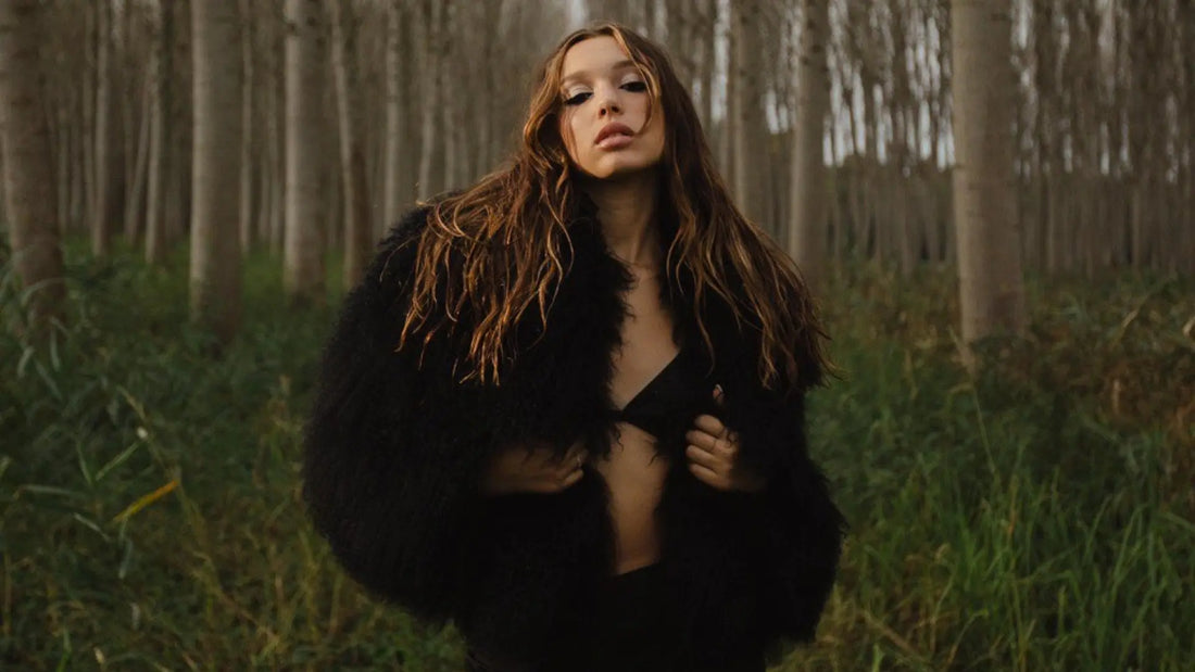 Sarah Toscano in un bosco di pioppi con una giacca in pelliccia nera, collaborazione Horda Brand