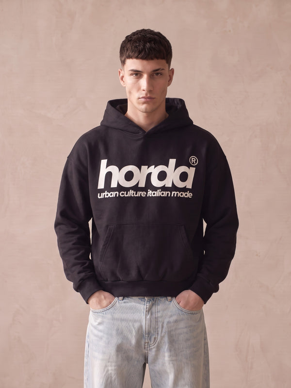 Felpa con cappuccio nera boxy fit Horda con scritta bianca "horda urban culture italian made" sul davanti, indossata con jeans chiari