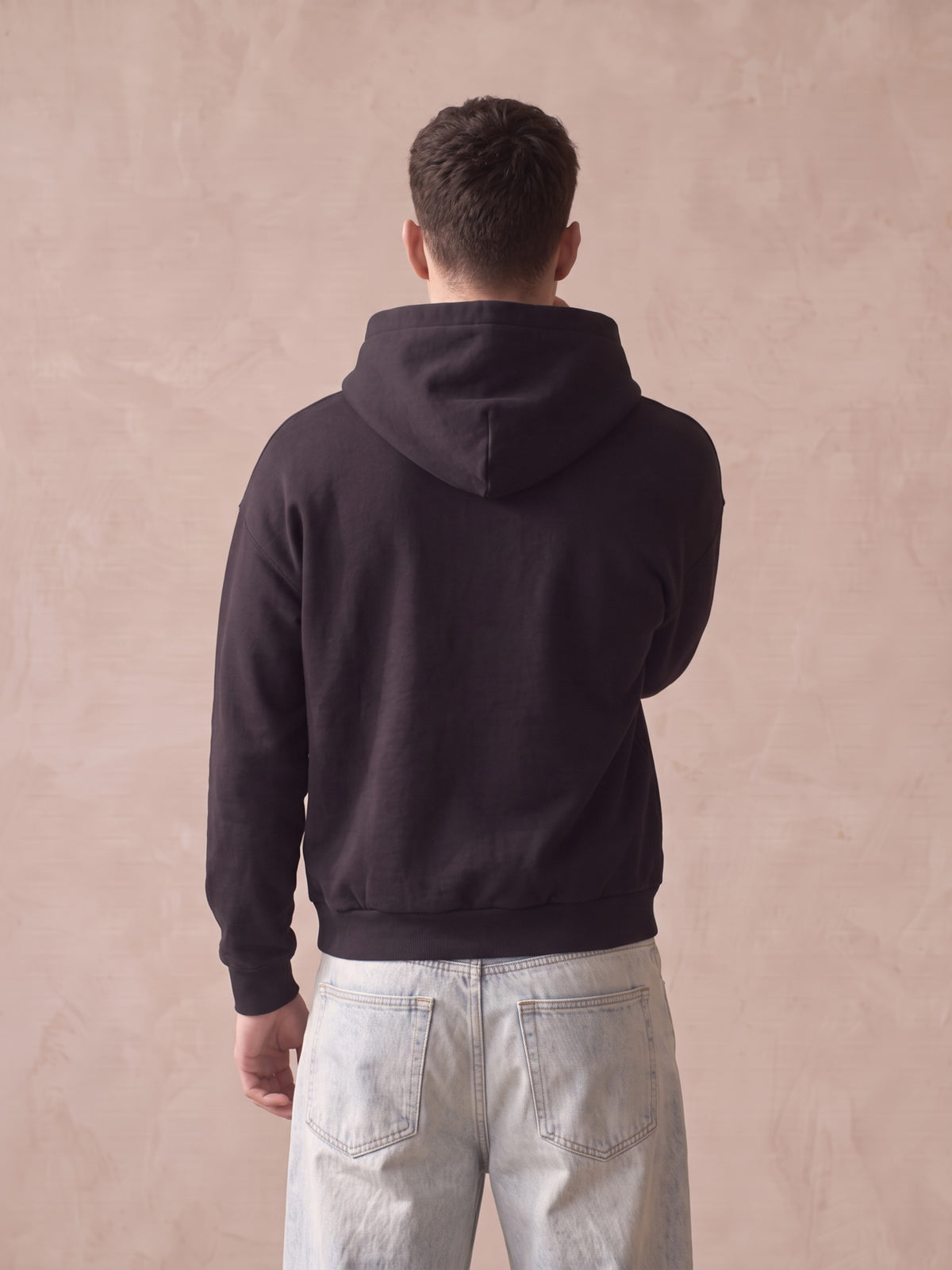 Retro di felpa nera con cappuccio senza stampe, vista posteriore con jeans chiari